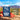 A pouch of Road Trip Mushroom Gummies is shown on a rocky surface with strawberries and several pink gummies in front. The background is a blurred outdoor desert landscape under a blue sky.