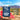 A pouch of Road Trip Mushroom Gummies is shown in a desert stardust landscape with watermelon slices and gummies. The packaging is dark blue with white text, and the background features a blue sky and sandy ground.